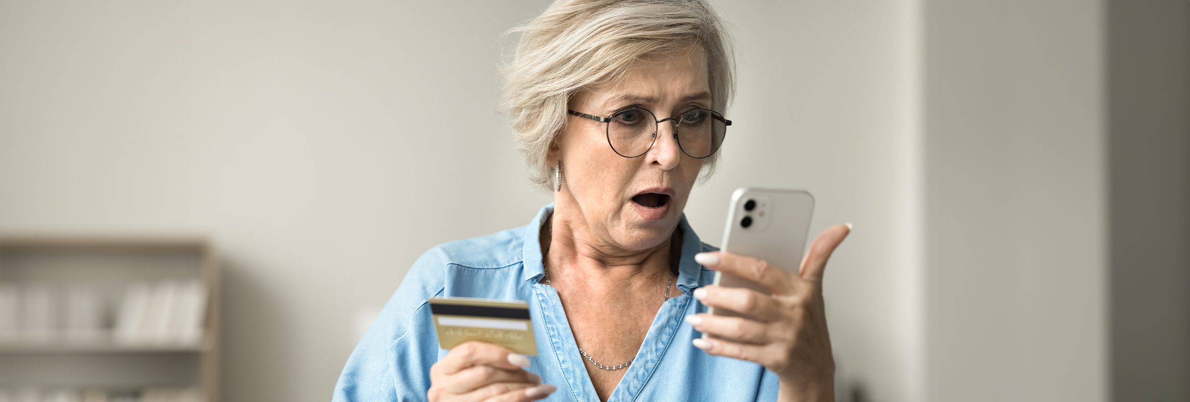 lady holding credit card and phone in shock